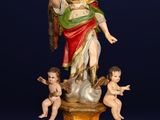 une statue ancienne représentant une femme entourée d'anges, posée sur un socle