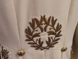 a white dress with gold embroidery and a wreath on the back