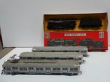 trois trains miniatures posés sur une table à côté d'une boîte