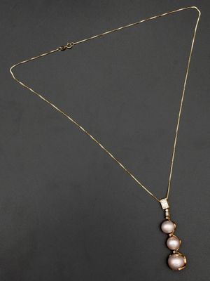un collier en or auquel sont suspendues trois perles