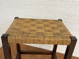 a wooden stool with a woven seat on top of it