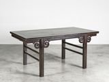 une vieille table avec un plateau en bois posée sur un sol en béton