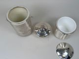 a silver container and a silver cup on a white table