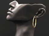 un gros plan sur la tête d'un mannequin portant une paire de boucles d'oreilles créoles en or
