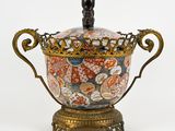 a vase with a lid that is decorated with flowers and leaves