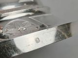 a person that is holding a silver watch in their hand