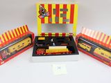 Trois trains miniatures emballés sont posés dans une boîte, sur une surface blanche.