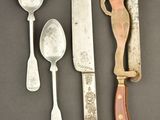 several different types of knives and spoons sitting on a table