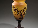 yellow and brown vase sitting on top of a wooden stand