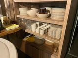 many plates and bowls on the shelves in the kitchen