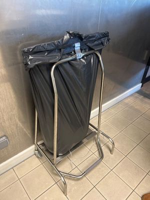 une poubelle munie d'un sac noir, posée sur un support métallique