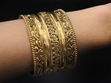 a close up of a woman ' s arm wearing a gold bracelet