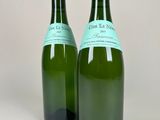 two bottles of wine with labels on them sitting next to each other