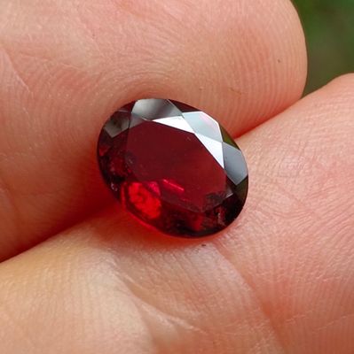 une personne tient un diamant rouge dans la main, sur un fond vert