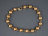 gros plan d'un bracelet en or sur une surface grise