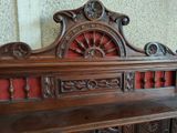 a wooden bench with carvings on it in front of a wall