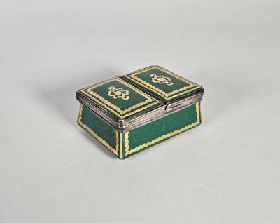 une image représentant une petite boîte verte et dorée posée sur une surface blanche