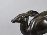 bronze sculpture of a camel on a pedestal against a gray background