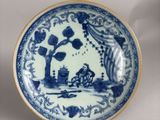 a blue and white plate with a picture of a man on a boat