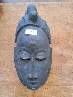 a black mask on a wooden table with a tag on it