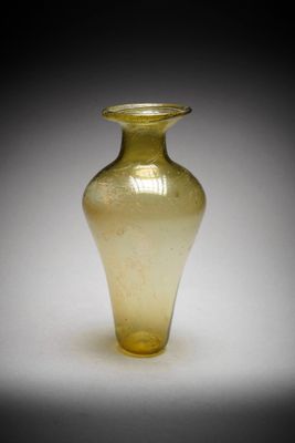 un vase en verre jaune posé sur une surface blanche