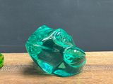 a green glass object sitting on a table next to a small green object