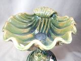 a green vase with a large shell on top of it