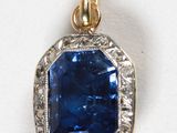 un gros plan d'un pendentif en saphir bleu et diamants sur une surface blanche