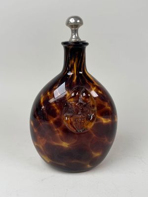 une bouteille en verre marron et noir ornée d'un crâne