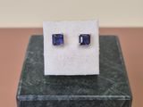 une paire de boucles d'oreilles à clous en saphir bleu posées sur un bloc de marbre