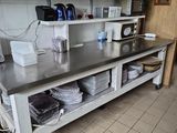 une cuisine avec un plan de travail en métal et des étagères sur lesquelles sont posés de la vaisselle