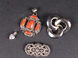trois bijoux en argent et en corail posés sur un fond noir
