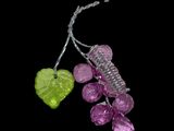 purple and green glass bead with a green leaf on a black background