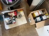 une boîte contenant divers objets, posée par terre à côté d'un aspirateur
