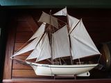 une maquette de voilier posée sur une étagère à côté d'un tonneau