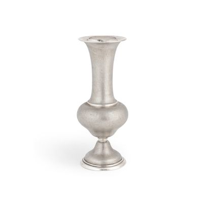 un vase en argent posé sur une surface blanche