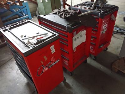 deux chariots à outils rouges contenant des outils, dans un garage