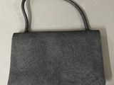 the small black purse is sitting on a white surface