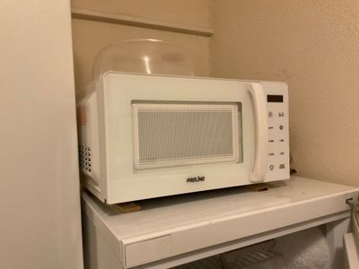 un micro-ondes posé sur une petite table blanche