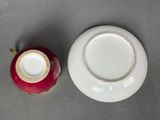 a small cup and saucer sitting next to each other