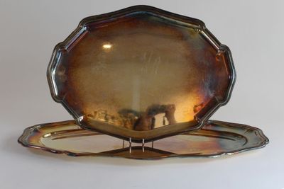 a silver plate on a stand on a white surface