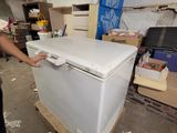 a woman standing next to a white refrigerator in a room