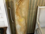 une grande colonne de marbre surmontée d'un élément en bois, dans une pièce