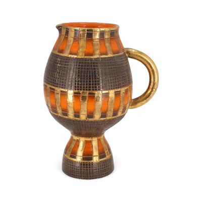 un vase marron et orange avec une anse dorée sur fond blanc