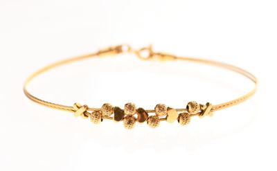 gros plan d'un bracelet en or sur fond blanc