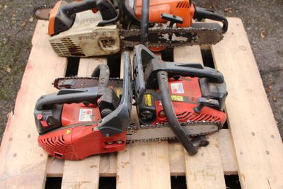 Plusieurs tronçonneuses sont posées sur une palette en bois.