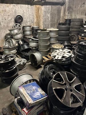 tires and rims are stacked on pallets in a garage