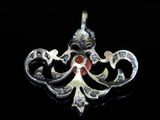 a close up of a silver pendant on a black surface