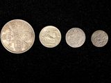 four silver coins are arranged in a row on a black surface