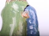 a green and blue vase sitting on a white table